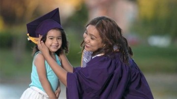 Graduate putting cap on young child