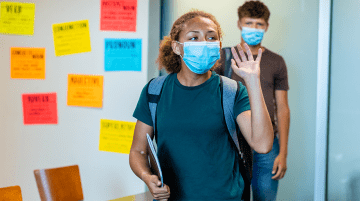 Middle school students entering a classroom wearing masks.