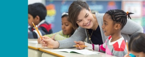 Female teacher assisting an elementary student with an assignment