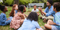 Teacher talking to group of young students outside on a lawn