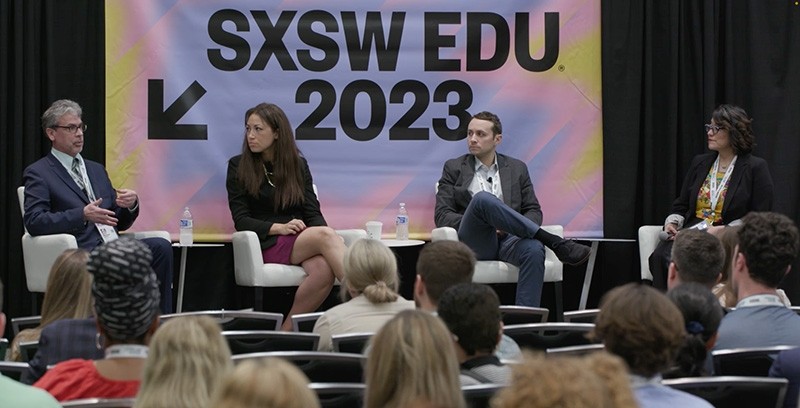 Michael Griffith speaks with 3 other panelists on a stage in front of a banner reading "SXSW EDU 2023"