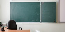 Empty classroom with a chalkboard and teacher's desk.