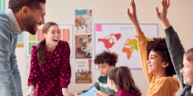 Students raising in hand in classroom with teachers