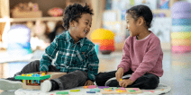 Two pre-K-aged children in a classroom laughing together