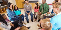 Group of adults and children smiling and seated in a circle.