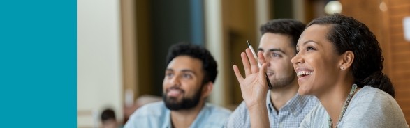 Two males and a women raising her hand while watching a presentation