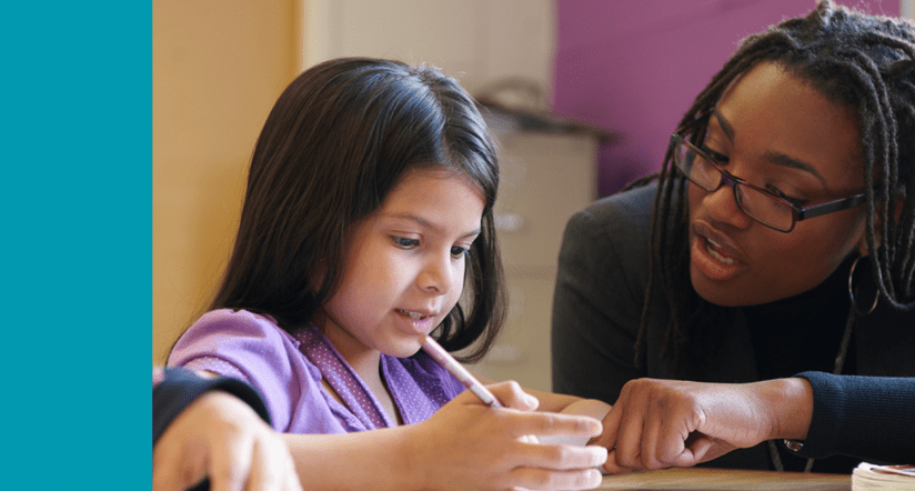 African American teacher instructing young student at table