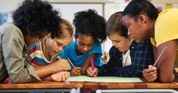 Diverse students working together at a table with markers