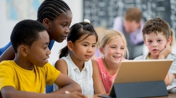 Elementary students working on a tablet.