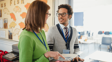 Two teachers talking in a classroom.