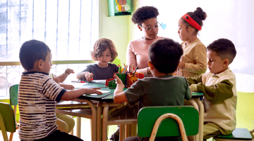 Teacher helping preschool students with a project.