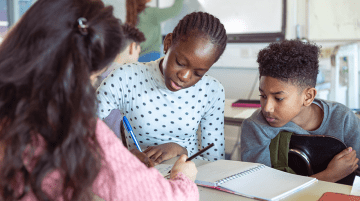 Teacher assisting two students with an assignment.