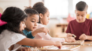 Preschool students working on a project while seated at a table.