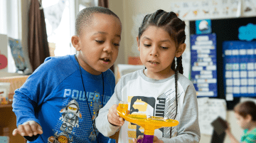 Two elementary students using a marble activity maze.