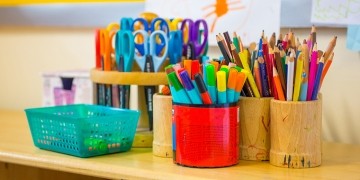 Colorful school supplies, including scissors, markers, and pencils, organized in cups and bins