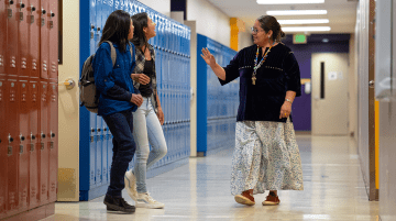 Students and teacher talking together in a hallway with lockers