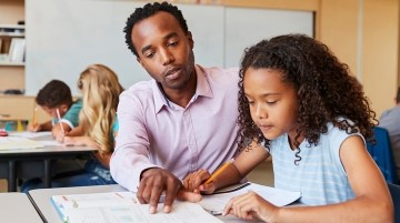 A teacher helping a student with an assignment in a classroom.