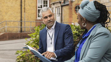 Two educators having a discussion outside of a school.