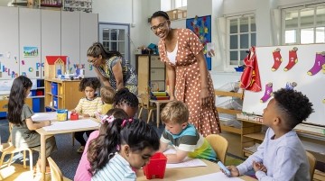 Two teachers engaging with elementary students in a classroom.