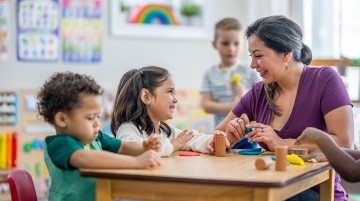 A teacher assisting preschool students in a classroom.