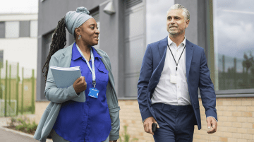 Two educators talking while walking outside.