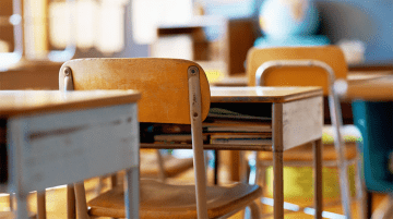 Close up of empty desks in a classroom.