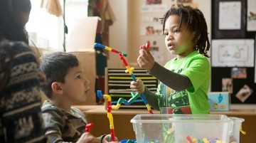Two young students playing with an educational toy.