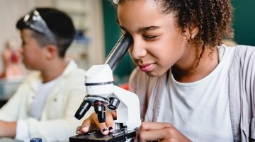 A middle school student looking through a microscope.