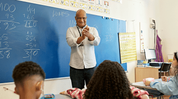 Teacher talking to student in front of classroom