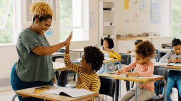 Teacher high-fiving student in classroom