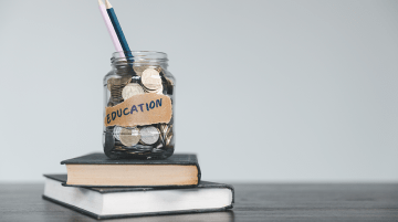 Jar of coins and pencils on a pile of school books
