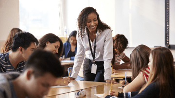 A teacher talking to a group of students in a classroom.