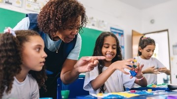 A teacher helping students finger paint.