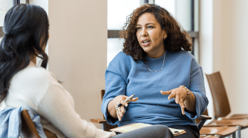 An educator and adult student having a discussion in a classroom.