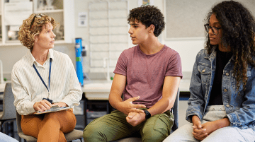 A counselor having a serious discussion with two high school students.