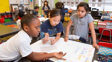 Three students working collaboratively on a school project.