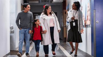 An educator talking with a family in a school hallway.