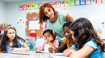 A teacher helping elementary students in a classroom