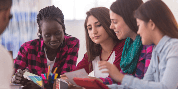 Group of high school students at a table reviewing materials