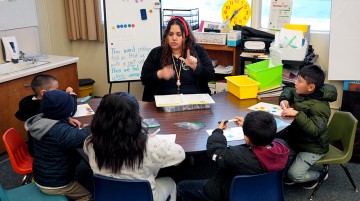 A teacher instructing a group of seated students.