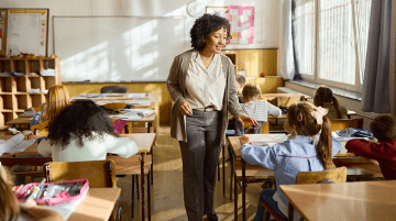 A teacher assists an elementary student in a classroom.