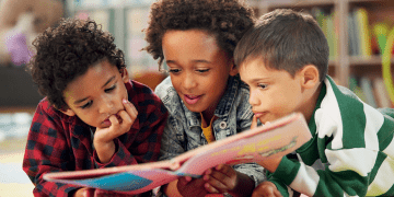 Children reading a book together on floor at school