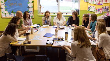 A group of educators having a discussion in a classroom.