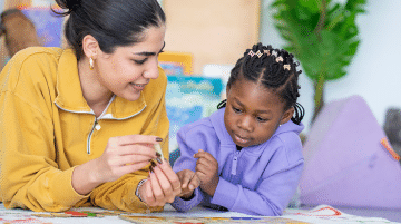 A teacher assists a preschool student with flash cards.