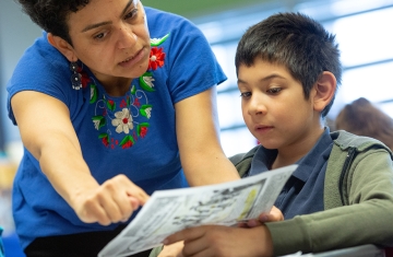 teacher helps young boy with classwork