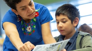 Teacher helping a young boy with an assignment on a piece of paper