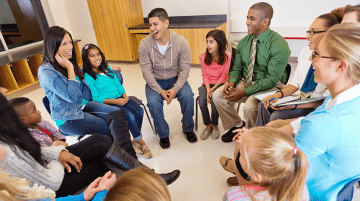 Group of adults and children smiling and seated in a circle.