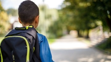 Young boy wearing a backpack facing away from the camera