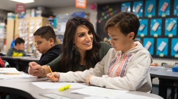 Teacher smiling at student working at desk