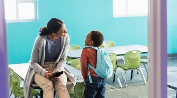 teacher talking to a student in a classroom